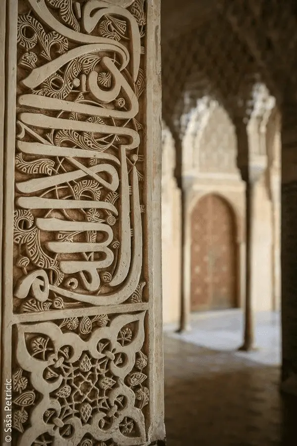 Calligraphie arabe sculptée dans la pierre, sous les arches d'un palais andalou