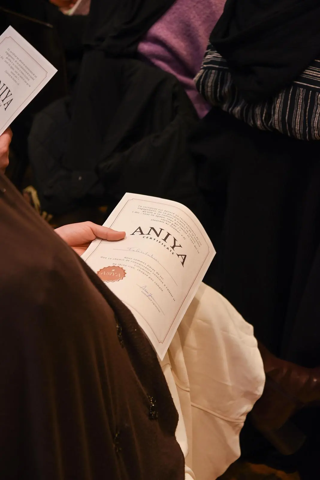 Une étudiante tenant son certificat ANIYA lors de la remise de fin de parcours